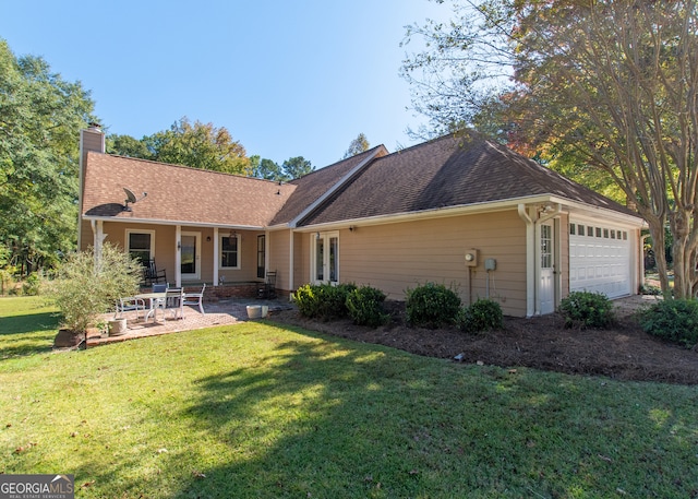 rear view of property with a yard and a garage