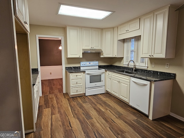 kitchen featuring white appliances, sink, dark stone counters, and dark hardwood / wood-style flooring