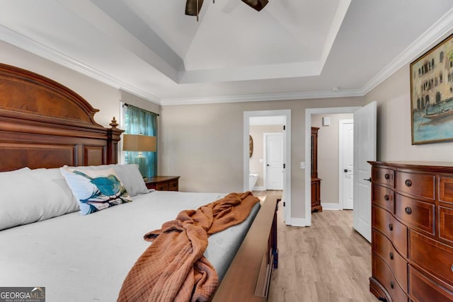 bedroom with ensuite bath, a tray ceiling, light hardwood / wood-style floors, ceiling fan, and ornamental molding