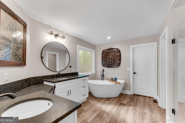 bathroom with vanity, wood-type flooring, and a bath