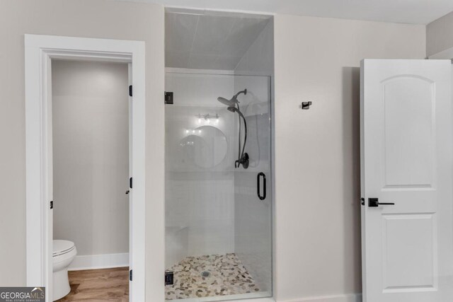 bathroom with toilet, hardwood / wood-style floors, and a shower with shower door