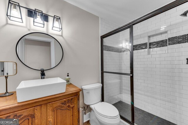 bathroom with vanity, a shower with shower door, and toilet