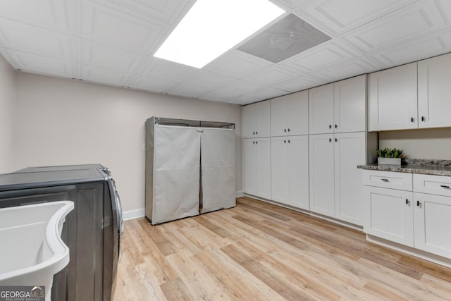 laundry area with washer and dryer, light hardwood / wood-style floors, and cabinets