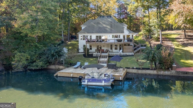 back of property with a deck with water view and a lawn