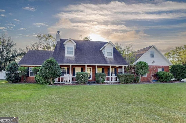 new england style home with a porch and a yard