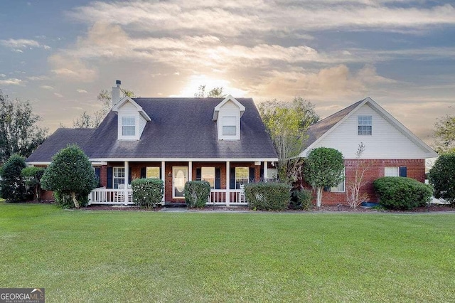 cape cod-style house with a yard and covered porch