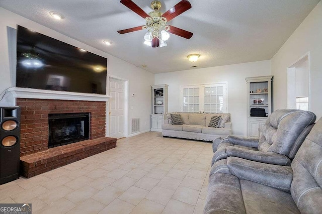 tiled living room with a textured ceiling, ceiling fan, and a brick fireplace