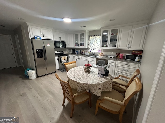 kitchen featuring appliances with stainless steel finishes, sink, light stone countertops, white cabinetry, and light hardwood / wood-style floors