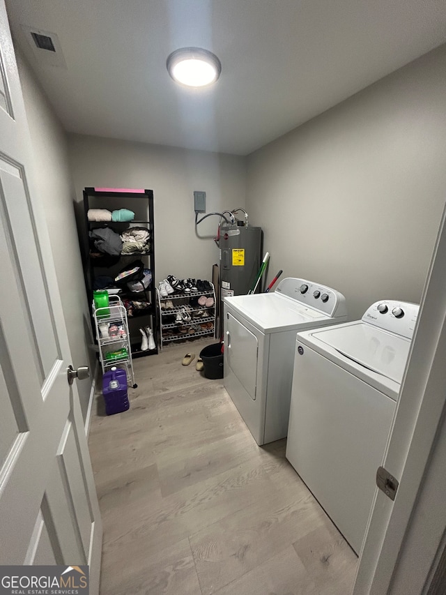 clothes washing area with light hardwood / wood-style flooring, water heater, and washing machine and clothes dryer