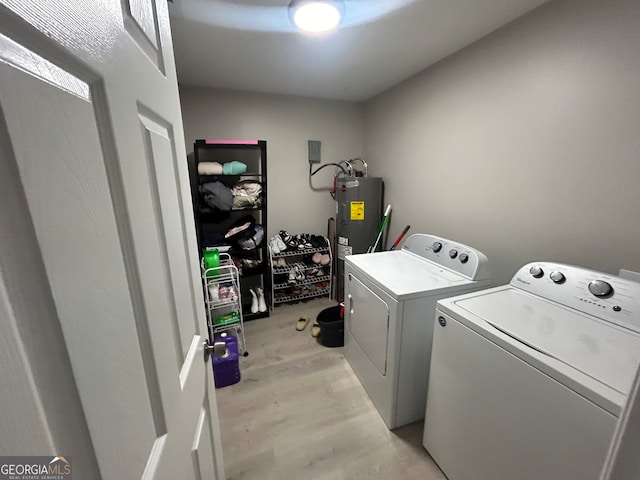 clothes washing area with light hardwood / wood-style floors, independent washer and dryer, and electric water heater