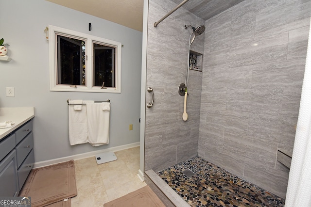 bathroom featuring vanity, tiled shower, and tile patterned flooring