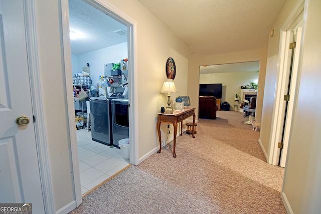 hall with a textured ceiling, light colored carpet, and separate washer and dryer