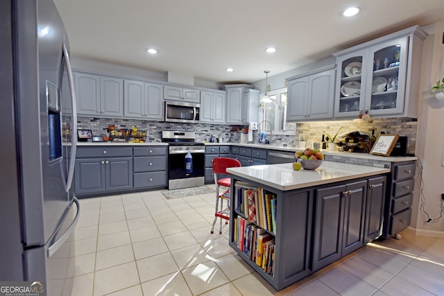 kitchen with decorative backsplash, gray cabinetry, stainless steel appliances, decorative light fixtures, and light tile patterned floors