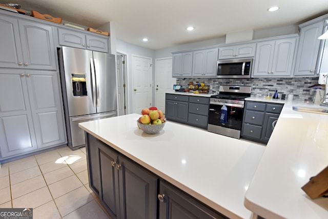 kitchen with decorative backsplash, gray cabinetry, stainless steel appliances, sink, and light tile patterned flooring