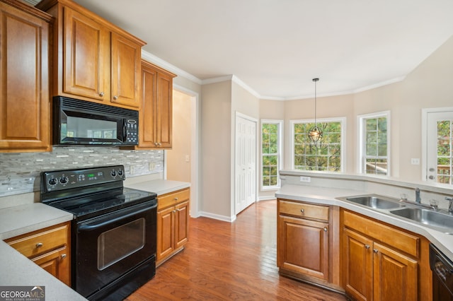 kitchen with black appliances, sink, light hardwood / wood-style floors, crown molding, and decorative light fixtures