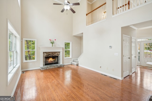 unfurnished living room featuring a towering ceiling, light wood-type flooring, and a wealth of natural light