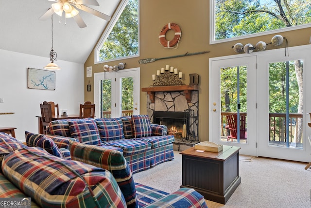 carpeted living room with high vaulted ceiling, ceiling fan, and a stone fireplace