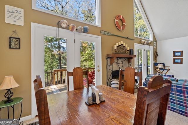 dining room featuring a high ceiling and a stone fireplace