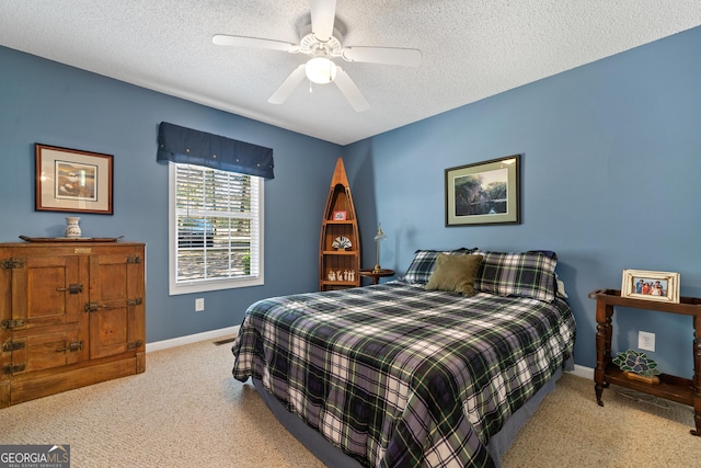 carpeted bedroom featuring ceiling fan and a textured ceiling