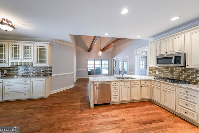 kitchen featuring cream cabinetry, appliances with stainless steel finishes, light hardwood / wood-style floors, and beamed ceiling