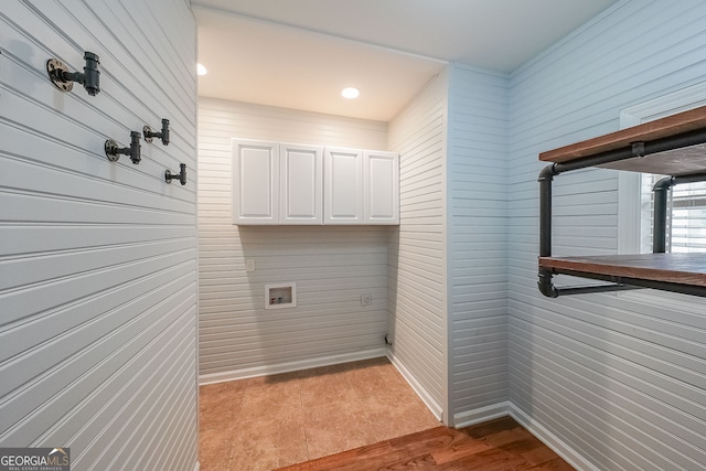 laundry room with washer hookup, light hardwood / wood-style floors, and cabinets