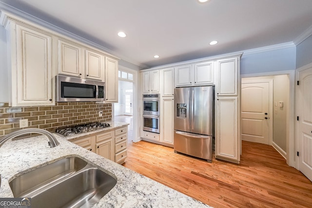 kitchen with sink, crown molding, decorative backsplash, light wood-type flooring, and stainless steel appliances