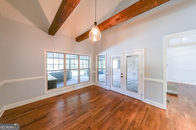 unfurnished room featuring french doors, lofted ceiling with beams, and hardwood / wood-style flooring