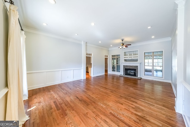 unfurnished living room featuring hardwood / wood-style floors, ceiling fan, and crown molding