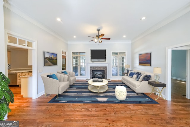 living room with a fireplace, wood-type flooring, ceiling fan, and ornamental molding