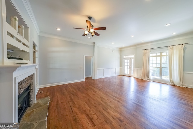 unfurnished living room with french doors, ceiling fan, ornamental molding, a fireplace, and wood-type flooring