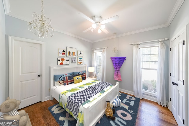 bedroom with dark hardwood / wood-style floors, ornamental molding, ceiling fan with notable chandelier, and multiple windows