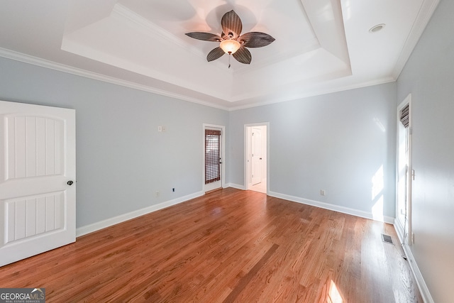 spare room with light hardwood / wood-style floors, a raised ceiling, ceiling fan, and ornamental molding