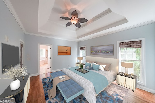 bedroom with hardwood / wood-style floors, ensuite bathroom, crown molding, ceiling fan, and a tray ceiling