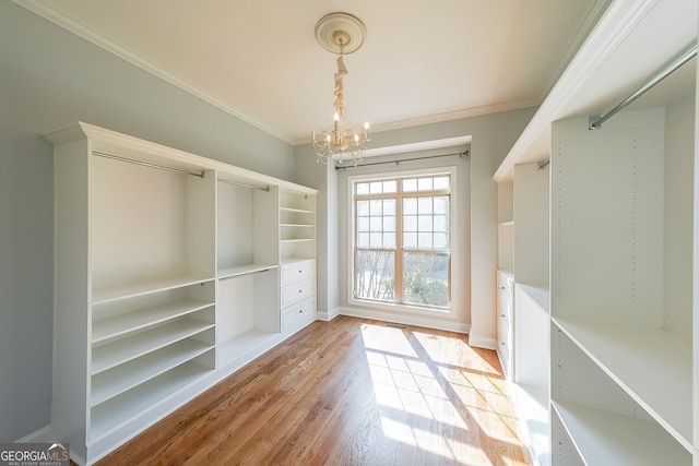 spacious closet with light hardwood / wood-style flooring and a chandelier