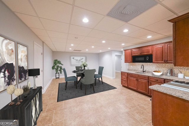 interior space featuring light tile patterned floors, a drop ceiling, and sink