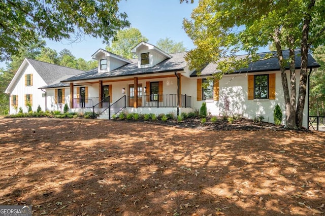view of front of property with a shingled roof, covered porch, and brick siding