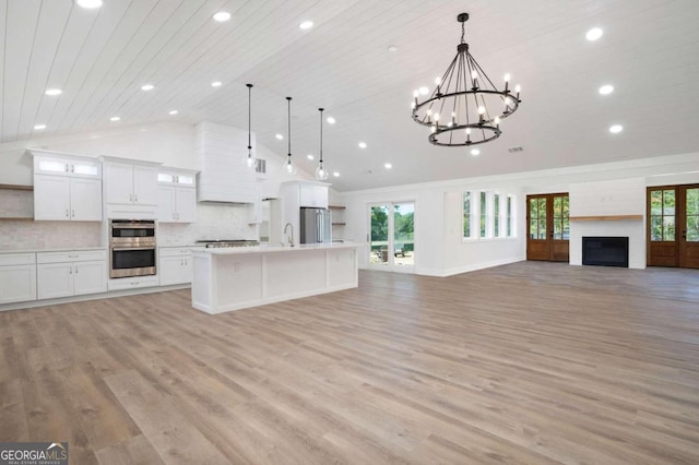 kitchen with recessed lighting, open shelves, appliances with stainless steel finishes, light countertops, and open floor plan