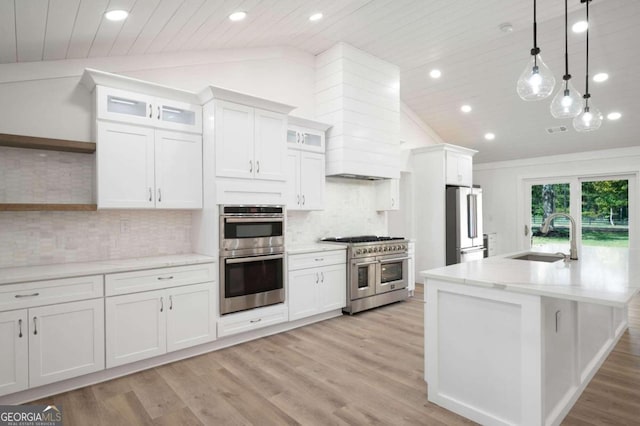 kitchen with lofted ceiling, hanging light fixtures, sink, premium appliances, and white cabinets