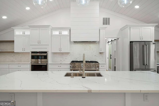 kitchen with white cabinetry, premium appliances, vaulted ceiling, and a barn door