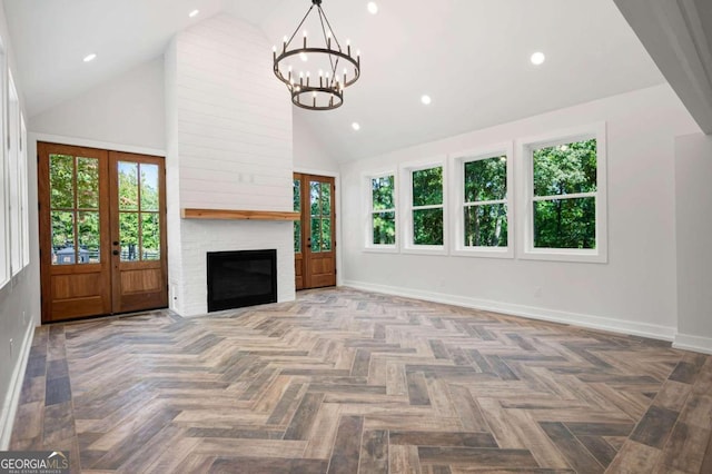 unfurnished living room with a fireplace, a notable chandelier, high vaulted ceiling, baseboards, and french doors