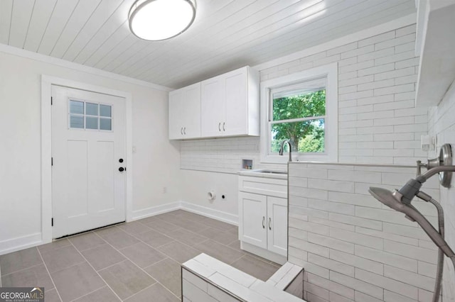 washroom featuring a sink, cabinet space, tile patterned floors, hookup for a washing machine, and ornamental molding