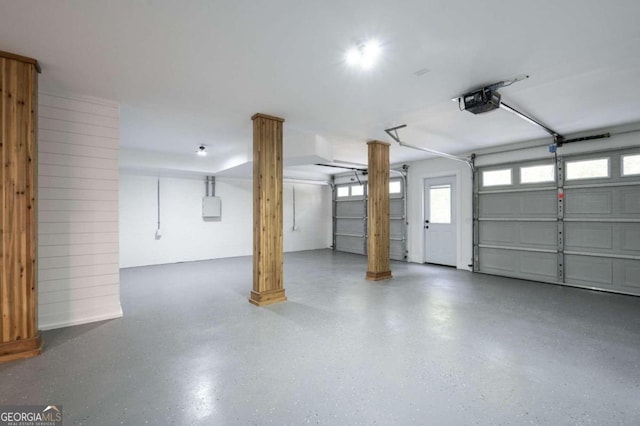 garage featuring a garage door opener, electric panel, and wooden walls