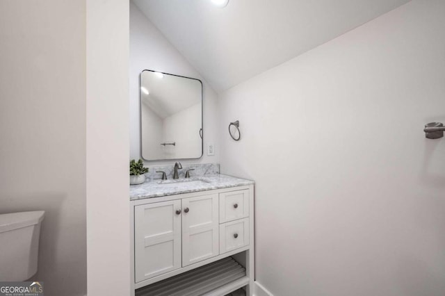 bathroom featuring vanity, toilet, and vaulted ceiling