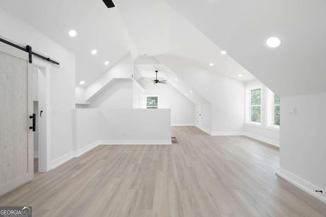 additional living space with ceiling fan, lofted ceiling, light hardwood / wood-style flooring, and a barn door