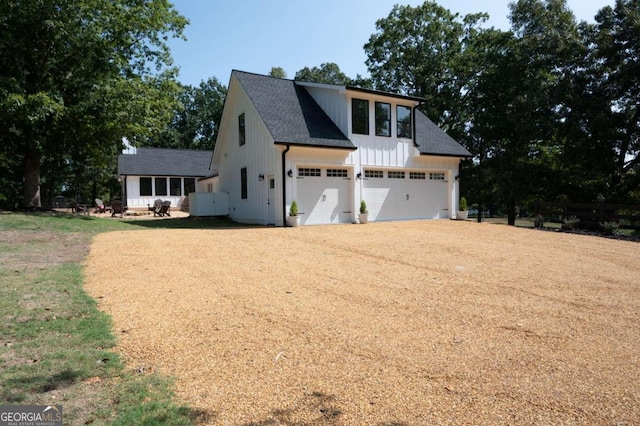 view of front of house with a garage, board and batten siding, driveway, and roof with shingles