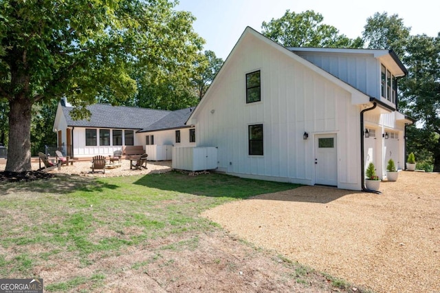 back of house with board and batten siding, dirt driveway, and a yard