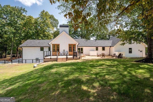 back of property featuring a deck and a lawn