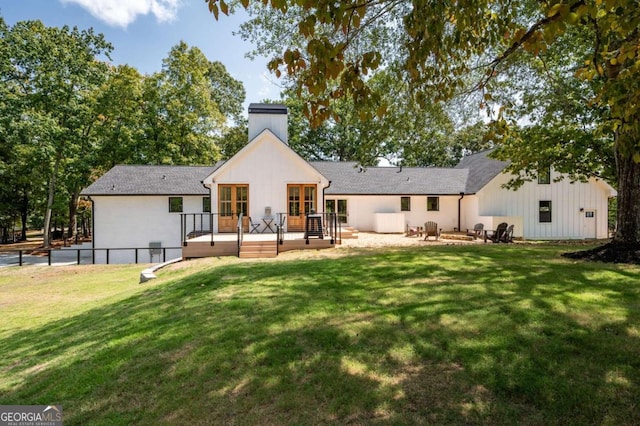 back of property with fence, a deck, a yard, and a chimney
