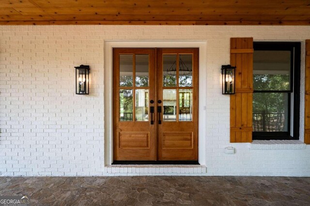 view of exterior entry with brick siding and french doors