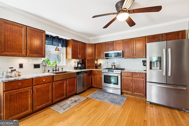 kitchen featuring light stone counters, backsplash, light hardwood / wood-style flooring, crown molding, and stainless steel appliances